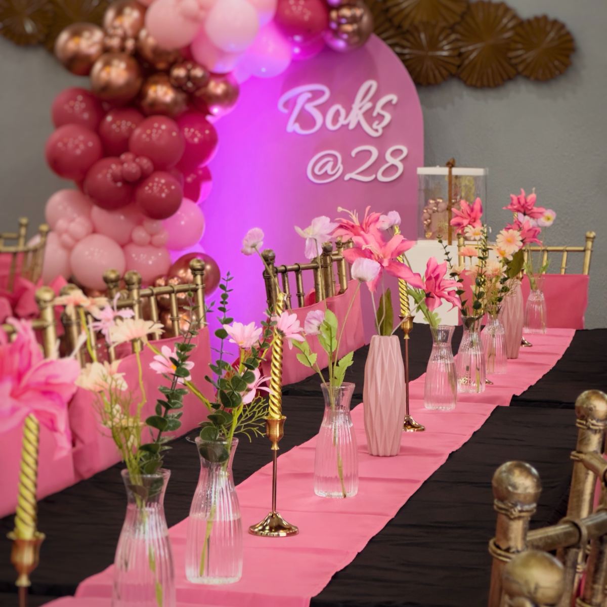 Pink and rose gold birthday tablescape with gold Tiffany chairs, bud vases and tapered candles