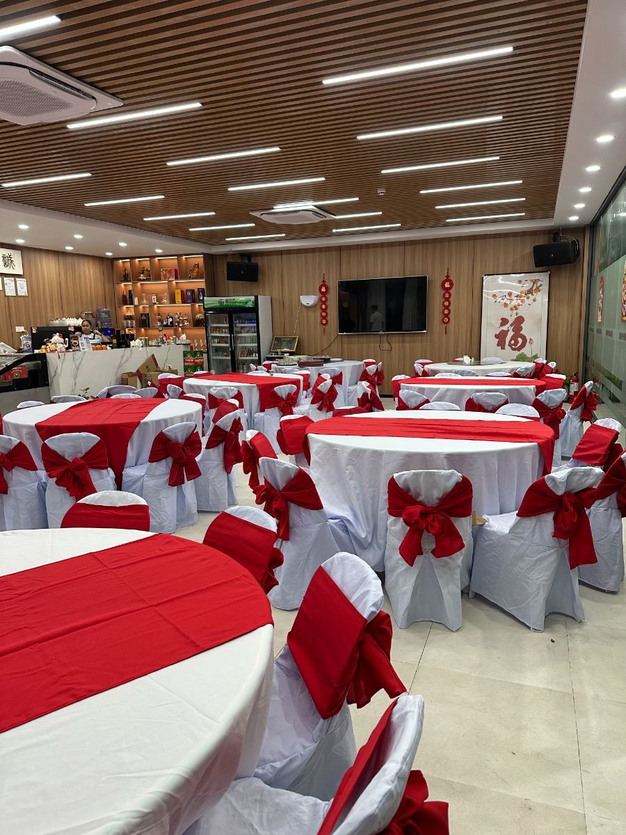 Round tables with white covers and red runners set up in a function hall