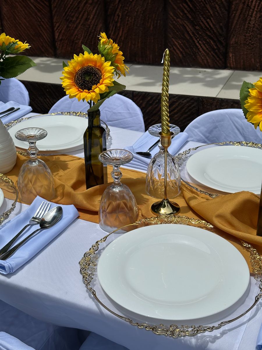 Styled tablescape with gold charger plates, sunflowers and candles at a Laguna event
