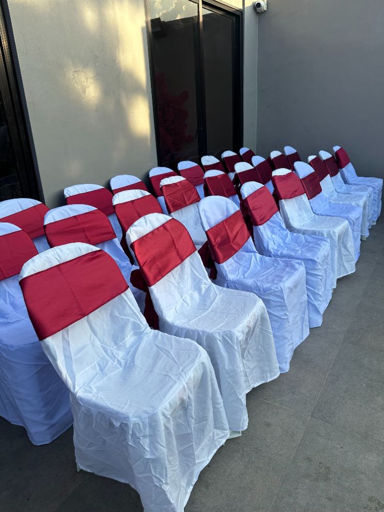 Monobloc chairs with white covers and coloured ribbons